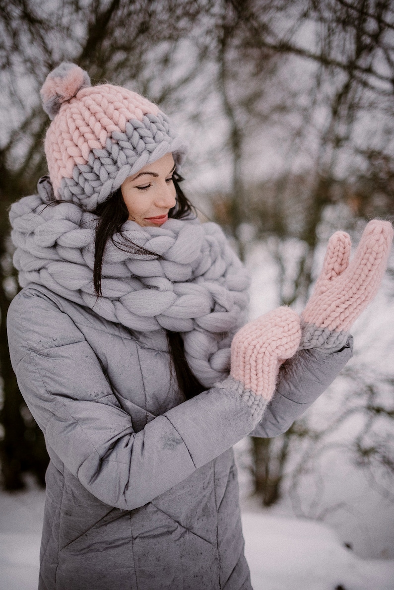 lady outdoors in winter wearing chunky knit mittens pom pom hat and scarf made of merino wool