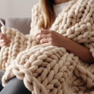 lady sitting on the couch with beige chunky knit blanket on top