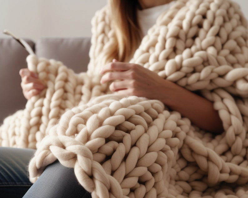lady sitting on the couch with beige chunky knit blanket on top