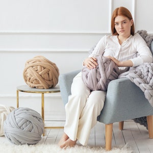 Lady sitting on an armchair ready to knit using Chunky knit yarn for arm knitting