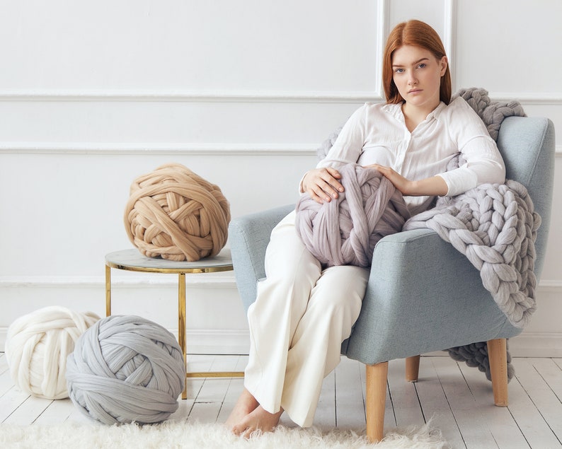 Lady sitting on an armchair ready to knit using Chunky knit yarn for arm knitting