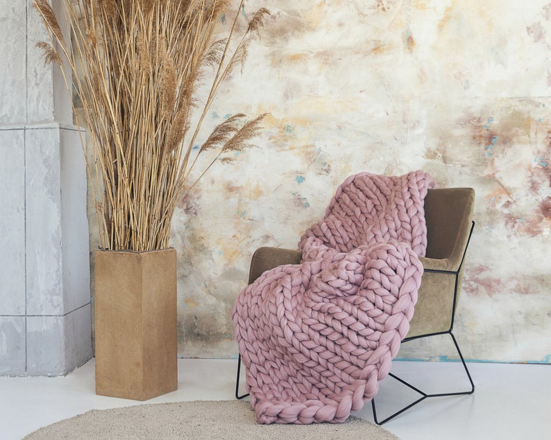 Dusty Pink chunky knit blanket on. chair in a cozy room