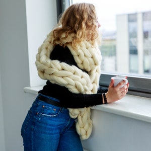 girl wearing chunky scarf in white looking through the window