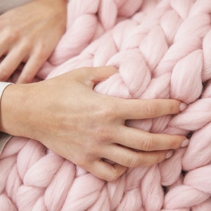 hands holding Super fluffy merino wool chunky blanket in baby pink