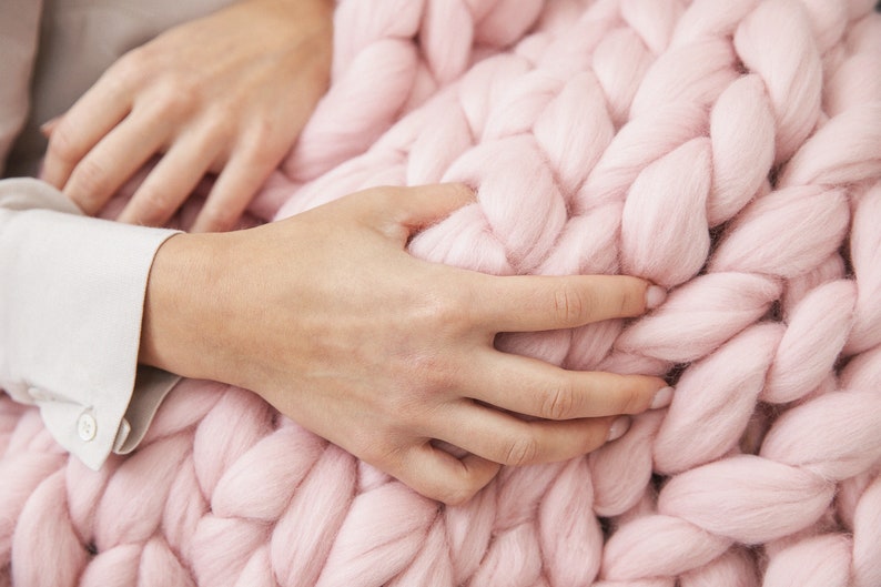 hands holding Super fluffy merino wool chunky blanket in baby pink