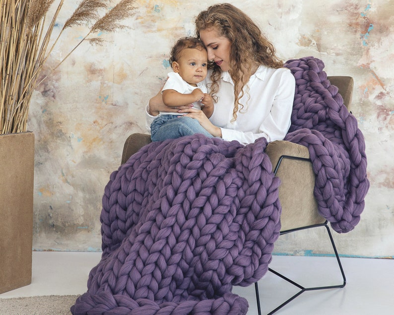 Lady with her baby sitting cozy with purple chunky blanket