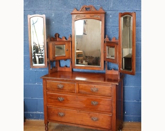 Tocador victoriano de nogal tallado con espejo sobre una cómoda.