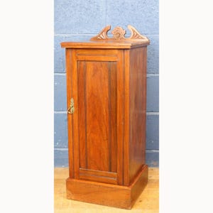 May include: A small, antique wooden cabinet with a rich, reddish-brown finish. The cabinet features a single door with a brass handle and decorative carving at the top. The cabinet is approximately 76 cm tall and is a classic piece of furniture.