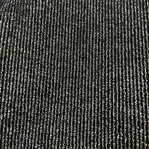 May include: Close-up of a black fabric with vertical silver metallic threads woven throughout. The threads create a shimmering, textured surface. The fabric has a subtle sheen, reflecting light and adding visual interest. The overall effect is a dark, elegant textile.