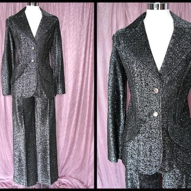 May include: A vintage black glitter suit, consisting of a blazer and matching pants. The blazer has a V-neck, two buttons, and pockets. The pants are wide-legged. The suit is displayed on a mannequin against a pink backdrop.
