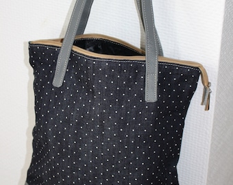 Sac zippé en tissu jean à pois et cuir gris avec anses en cuir avec doublure noire et poche intérieure.