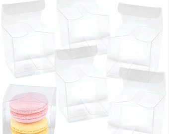 May include: Six clear plastic boxes with a flap top, perfect for packaging small gifts or treats. One box contains two pastel macarons.