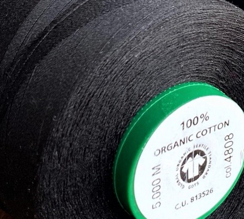 May include: A spool of black thread with a green label that reads "100% Organic Cotton 5,000 M C.U. 813526 col. 4808"