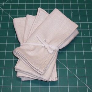 May include: A stack of four off-white linen napkins tied together with a white ribbon.