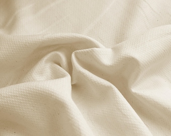 May include: Close-up of a textured, off-white fabric with a subtle woven pattern. The fabric is soft and drapes nicely.