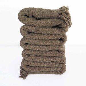 May include: A stack of five brown woven blankets with fringe on the ends.