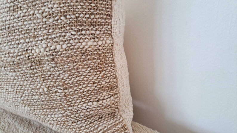 May include: Close-up of a beige woven throw pillow with a textured surface.