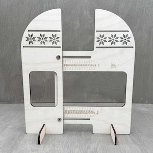 May include: A light-coloured wooden craft tool with a snowflake design and measurement markings. The tool has a rectangular cutout and two small feet. The text "KAI IRON" is visible.