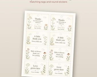May include: A printable sheet of eight rectangular baby shower favor tags featuring floral illustrations in muted tones. The text includes phrases like Thanks for showering us with love, A little thank you, Baby in bloom, and Love grows here.