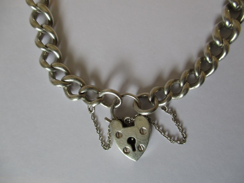 A vintage sterling silver curb link bracelet with a fully hallmarked for 1965 padlock heart clasp