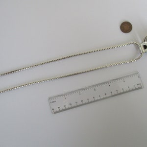 May include: A silver chain necklace with a silver pendant featuring a round, iridescent moonstone. The necklace is 18 inches long and is shown next to a ruler and a coin for size reference.