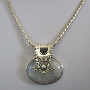 May include: A silver chain necklace with a silver pendant featuring a large oval moonstone.