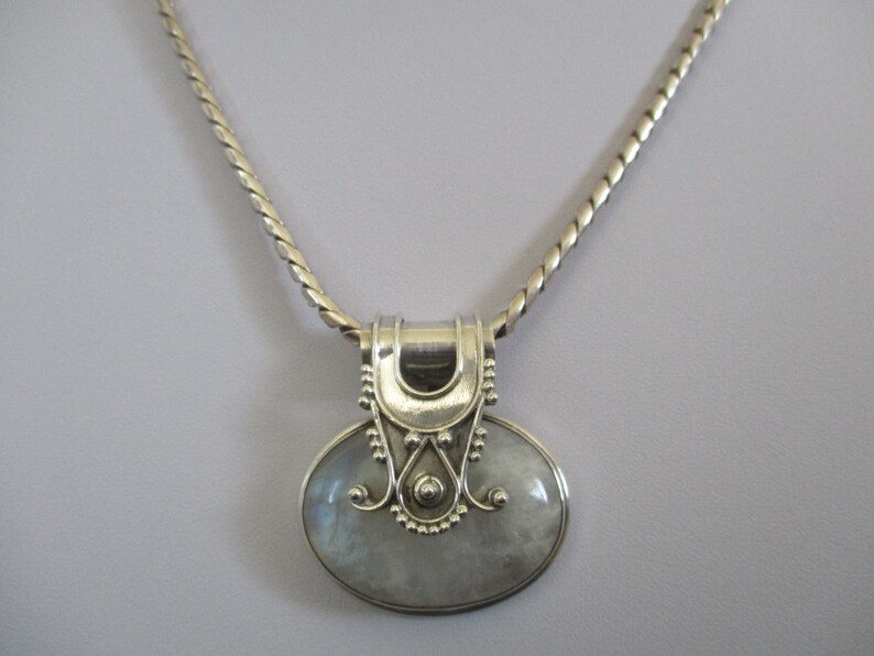 May include: A silver chain necklace with a silver pendant featuring a large oval moonstone.