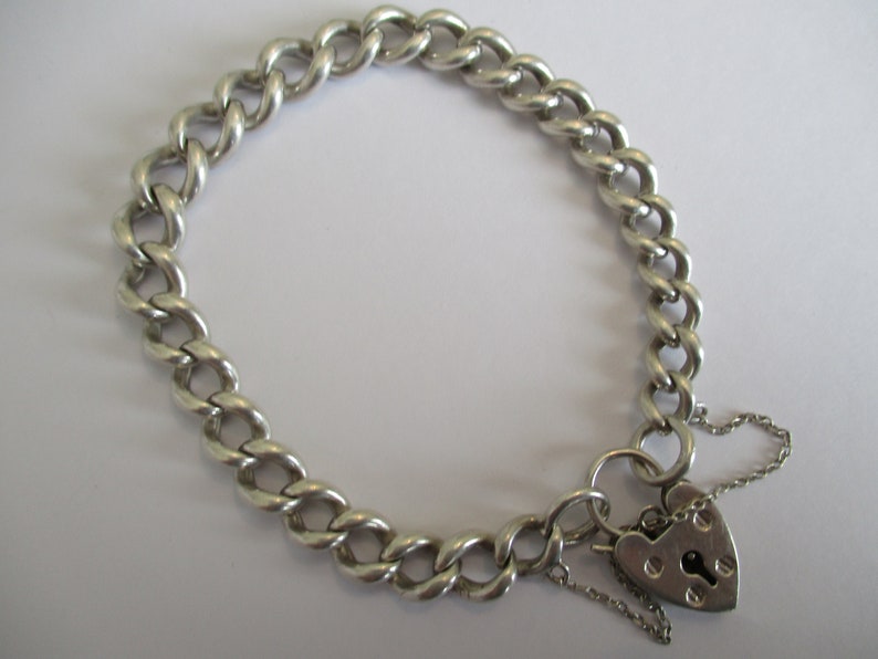 A vintage sterling silver curb link bracelet with a fully hallmarked for 1965 padlock heart clasp