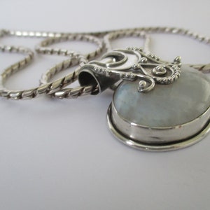 May include: A silver chain necklace with a heart-shaped pendant featuring a white iridescent stone.