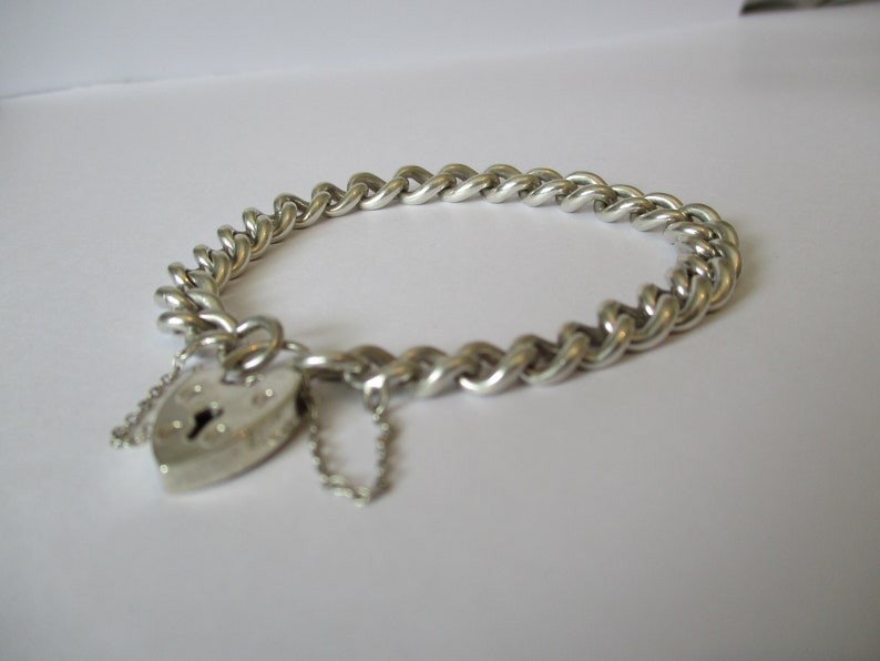 A vintage sterling silver curb link bracelet with a fully hallmarked for 1965 padlock heart clasp