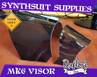 May include: Two clear plastic MK6 visors for a synthsuit. The visors are curved and have a dark tint. The text "VISOR ONLY!!" is on a yellow warning sign. The text "MK6 VISOR" is on a purple background. The text "Raptor's Den" is on a white background with a purple border.
