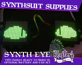 May include: Two black Synth Eye panels with green LED displays showing a stylized eye design. The text "SYNTHSUIT SUPPLIES" and "SYNTH EYE" are displayed in purple. The text "TWO PANELS, READY TO BUILD IN OPTIONAL BATTERY AND FAN SET" is also visible.