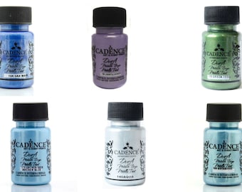 Könnte beinhalten: Acht Flaschen Cadence Deep Metallic Acrylic Paint in verschiedenen Blautönen, Grüntönen und Violetttönen. Jede Flasche hat einen schwarzen Deckel und ein Etikett mit dem Markennamen und der Produktbeschreibung.