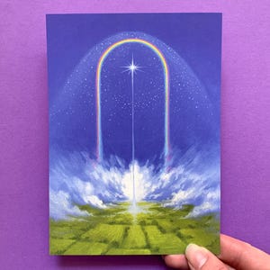 May include: An art print depicting a celestial landscape. A rainbow forms an arch above a bright star, with a beam of light descending to a green field. The sky is a deep blue, speckled with stars, and the clouds are white and fluffy.