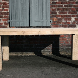 K&ouml;nnte beinhalten: Ein heller Holz-Esstisch mit rechteckiger Tischplatte und vier Beinen. Der Tisch steht vor einer Backsteinwand mit einem geschlossenen Fensterladen.