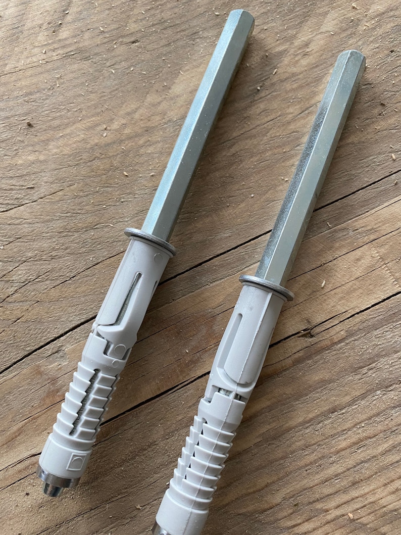 May include: Two silver and white plastic drywall anchors with a hexagonal head. The anchors are designed to be used with screws to secure objects to drywall.