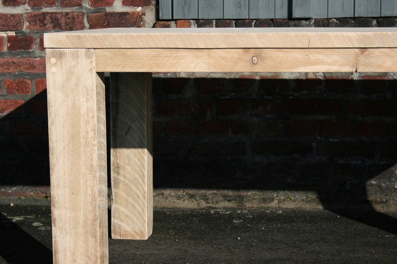 K&ouml;nnte beinhalten: Nahaufnahme eines hellen Holztisches mit nat&uuml;rlicher Oberfl&auml;che. Der Tisch hat ein schlichtes Design mit einer rechteckigen Tischplatte und vier Beinen. Der Tisch ist aus massivem Holz gefertigt und hat einen rustikalen Look.