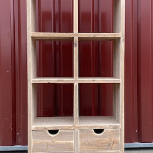 Könnte beinhalten: Ein rustikales Holzregal mit sechs offenen Regalbrettern und zwei Schubladen. Die Regalbretter und Schubladen sind aus recyceltem Holz gefertigt und haben eine natürliche, gewitterte Oberfläche.