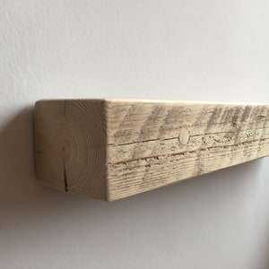 May include: A rustic wooden shelf with a natural finish. The shelf is made from reclaimed wood and has a knot hole on the top surface.