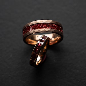 Peut inclure: Deux bagues en or avec une incrustation de pierres précieuses rouges. Les bagues sont empilées l'une sur l'autre.