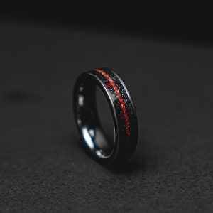 Könnte beinhalten: Ein schwarzer Ring mit einer roten und schwarzen Einlage. Der Ring ist aus einem strapazierfähigen Material gefertigt und hat ein elegantes, modernes Design.
