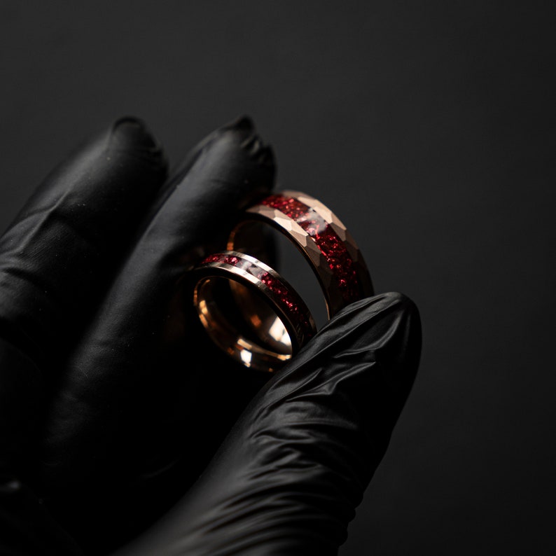 K&ouml;nnte beinhalten: Zwei Ringe aus Ros&eacute;gold mit einer roten Glitzer-Einlage. Die Ringe sind &uuml;bereinander gestapelt.