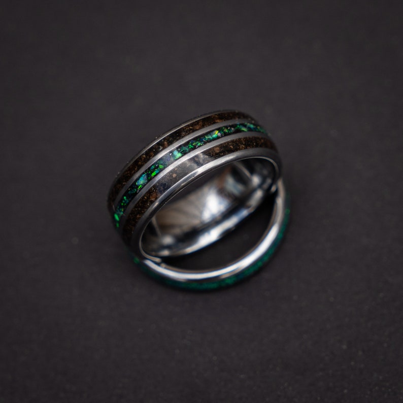 May include: Two silver rings with a black and green inlay. The rings are stacked on top of each other.