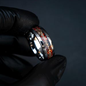 Op de afbeelding: Een zilveren ring met een rode en gouden inlay. De ring is breed en heeft een gepolijste afwerking.