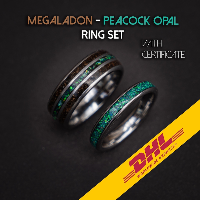 May include: Two wedding bands, one with a black and green peacock opal inlay and the other with a brown and green peacock opal inlay. The rings are made of tungsten carbide and are both polished to a high shine. The text "MEGALADON - PEACOCK OPAL RING SET WITH CERTIFICATE" is displayed above the rings.