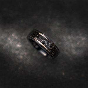 May include: A black and gold ring with a unique design. The ring has a thin gold band and a black band with a pattern of white dots.