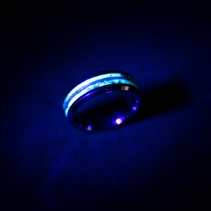 May include: A black ring with two white stripes that glow in the dark.