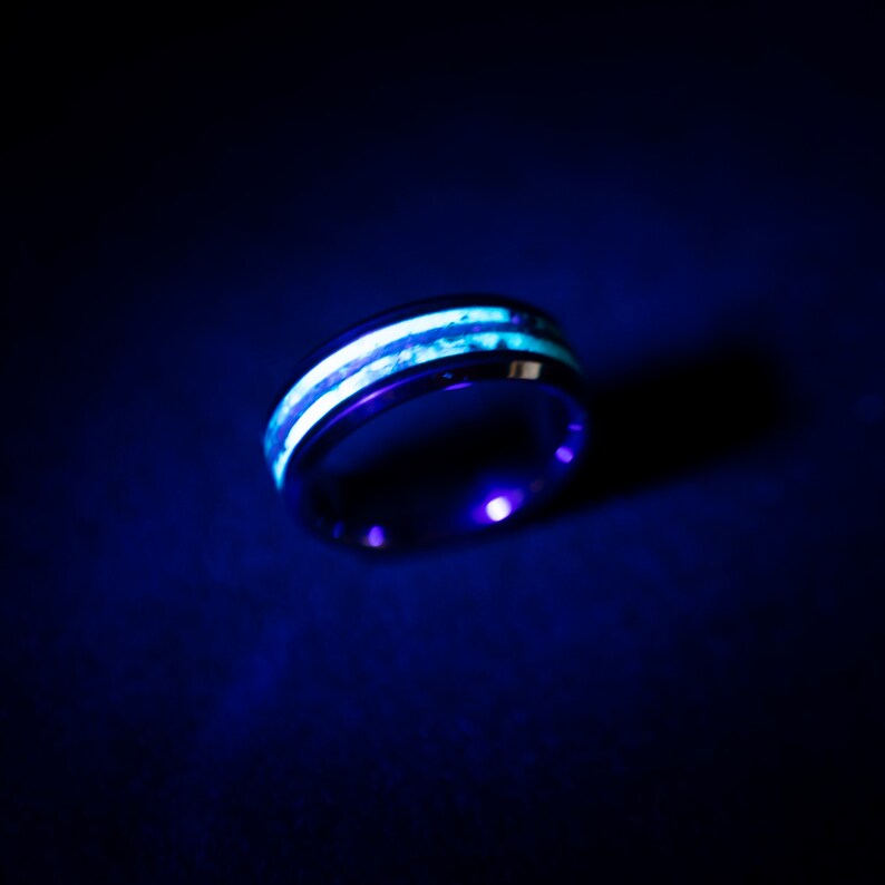 May include: A black ring with two white stripes that glow in the dark.