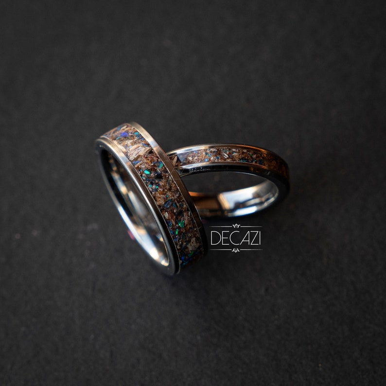 May include: Two silver rings with brown and blue inlay. The rings are stacked on top of each other. The rings are made of metal and have a polished finish.