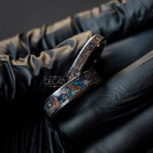 May include: Two silver rings with a brown and blue inlay. The rings are stacked on top of each other.